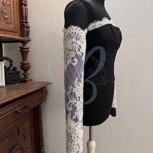 May include: A black lace top with long white lace sleeves. The top has a sweetheart neckline and is fitted.
