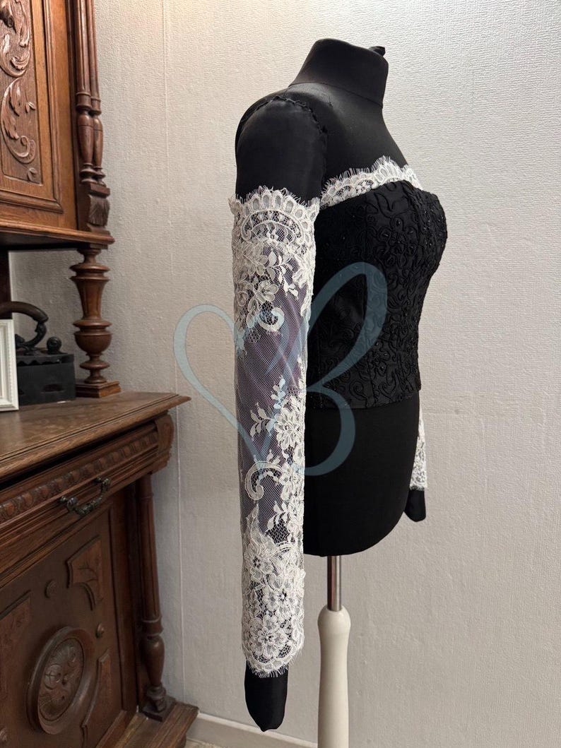 May include: A black lace top with long white lace sleeves. The top has a sweetheart neckline and is fitted.