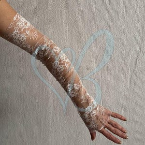 K&ouml;nnte beinhalten: Wei&szlig;e Armhandschuhe aus Spitze mit floralen Mustern. Die Handschuhe reichen von den Fingerspitzen bis zum Oberarm. Die Spitze ist detailliert und zart und sorgt f&uuml;r einen romantischen und eleganten Look. Ideal f&uuml;r Hochzeiten oder besondere Anl&auml;sse.