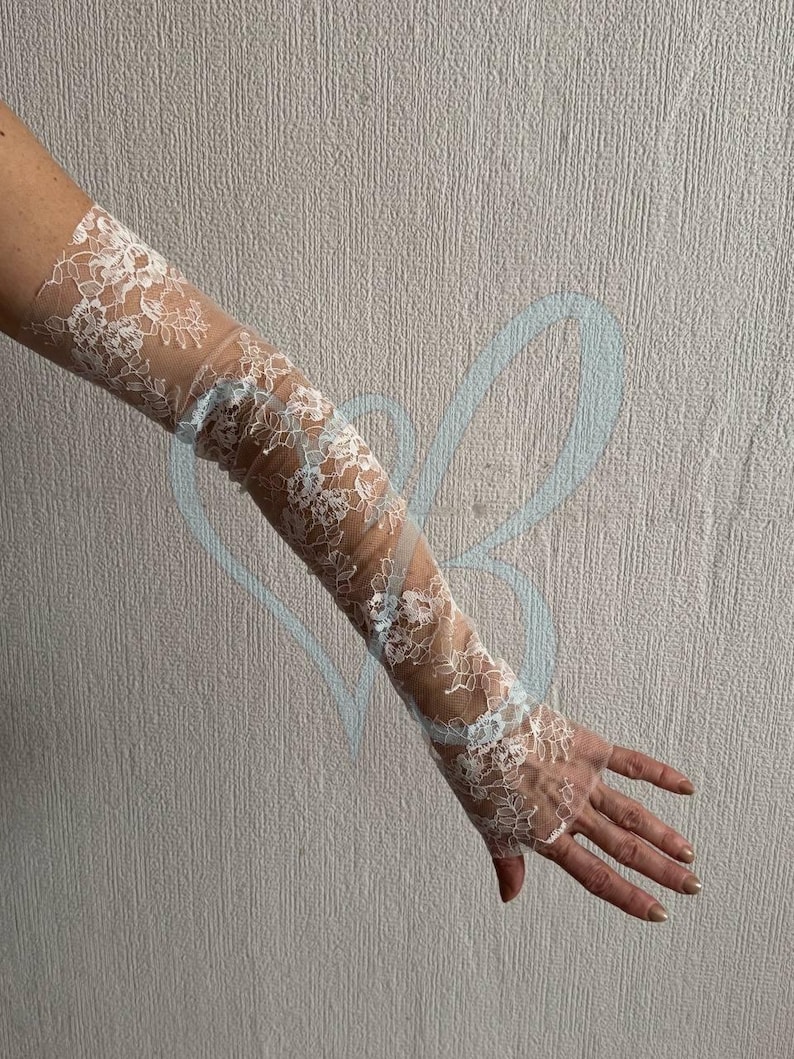 K&ouml;nnte beinhalten: Wei&szlig;e Armhandschuhe aus Spitze mit floralen Mustern. Die Handschuhe reichen von den Fingerspitzen bis zum Oberarm. Die Spitze ist detailliert und zart und sorgt f&uuml;r einen romantischen und eleganten Look. Ideal f&uuml;r Hochzeiten oder besondere Anl&auml;sse.