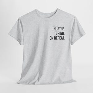 May include: A grey t-shirt with the text "Hustle. Grind. On Repeat." printed on the front.