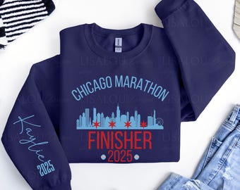 May include: Navy blue sweatshirt with the text "Chicago Marathon Finisher 2025". The design includes a skyline graphic and the name "Kaylie" with the year 2025 on the sleeve.