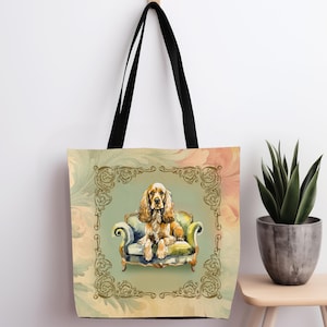 May include: A beige tote bag with a black handle features a watercolour illustration of a cocker spaniel sitting in a green armchair. The background is a vintage-inspired floral pattern with gold accents.