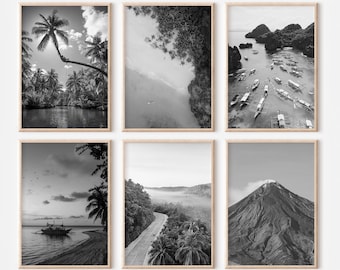 Op de afbeelding: Set van zes zwart-wit landschapsfoto's in houten frames. De foto's tonen een tropisch strand, een weelderig bos, een bergketen, een boot op een meer, een weg door een bos en een groep boten in een baai.