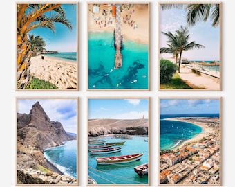 May include: Six framed landscape prints featuring beach and ocean scenes. The prints showcase sandy beaches, turquoise waters, palm trees, boats, and coastal towns. The images are in wooden frames.