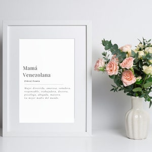 Puede incluir: Una impresi&oacute;n enmarcada con fondo blanco y texto negro. El texto dice "Mam&aacute; Venezolana" y una definici&oacute;n en espa&ntilde;ol. La impresi&oacute;n est&aacute; sobre una superficie blanca con un ramo de rosas rosas y blancas en un jarr&oacute;n blanco.