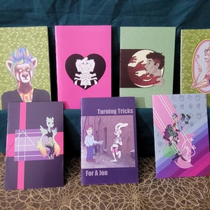 May include: A collection of eight small, colourful, paperback books with various illustrations and titles. The books are arranged in two rows on a patterned surface. The titles include "Turning Tricks" and "For A Jon".