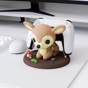 May include: A brown and tan deer figurine with black eyes and white spots, sitting on a brown base with red and white mushroom accents. A white game controller is behind the deer.