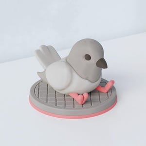 May include: A gray and white bird figurine with a dark beak and eyes, perched on a gray platform with a pink rim. The bird's pink feet are visible. The figurine has a cartoonish design.