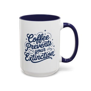 May include: White ceramic coffee mug with a navy blue rim and handle. The mug features a navy blue graphic that says "Coffee Prevents Your Extinction" with a small coffee cup and dinosaur illustration.