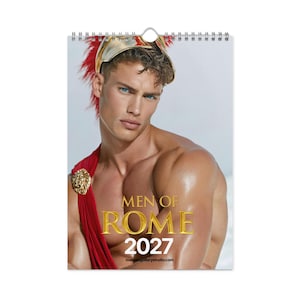 Könnte beinhalten: Ein Wandkalender für 2027 mit dem Porträt einer Person, die einen goldenen Helm mit rotem Federbusch und eine rote Schärpe mit goldenem Löwenemblem trägt. Der Text lautet MEN OF ROME 2027 in goldener und weißer Schrift auf hellgrauem Grund.