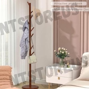 May include: A brown wooden coat rack with multiple branches for hanging clothes and accessories. The rack is standing in a room with a white wall and a white nightstand with two drawers. The text "Attractive and Sleek" and "Matching Any Home Decor" is visible in the image.