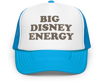 May include: A trucker hat with a white front panel and a bright blue brim and mesh back. The text "BIG DISNEY ENERGY" is printed in brown block letters on the front panel. The hat has a curved brim and a snap closure.