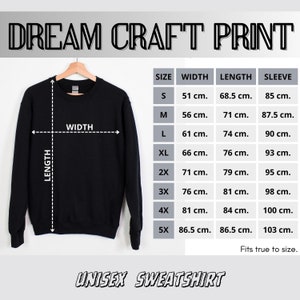 May include: Black unisex sweatshirt displayed on a hanger, with a size chart showing measurements in centimeters. The text "DREAM CRAFT PRINT" is at the top, and "UNISEX SWEATSHIRT" at the bottom. The chart includes width, length, and sleeve measurements.