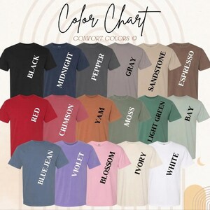 May include: A color chart displaying a variety of Comfort Colors t-shirts. The shirts are arranged in rows and columns, showcasing colors like black, red, and blue jean. The text "Color Chart" is written at the top.