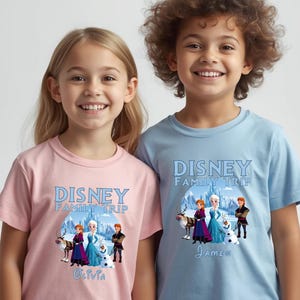 May include: Two children wearing matching t-shirts. The shirts are light pink and light blue, each with a "Disney Family Trip" graphic featuring characters from the movie Frozen. The pink shirt has the name "Olivia" and the blue shirt has the name "James".
