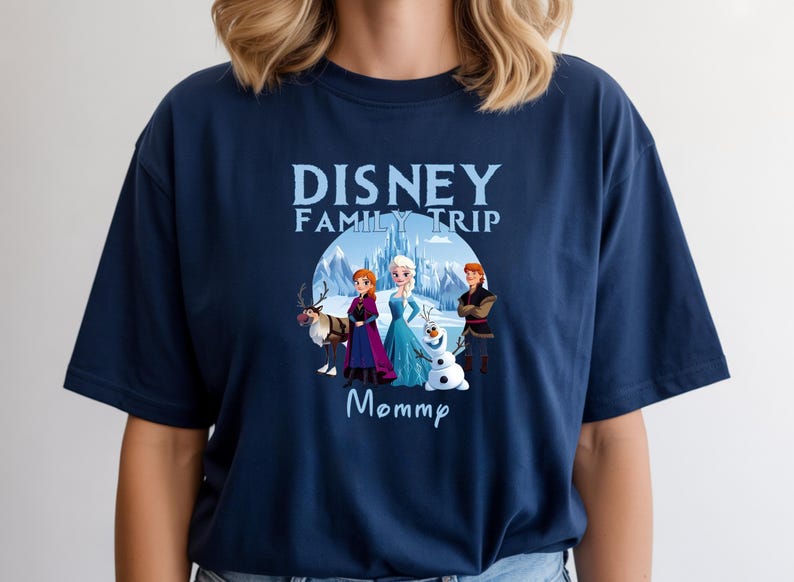 May include: Navy blue t-shirt featuring a graphic of characters from the Disney movie Frozen, including Elsa, Anna, Kristoff, and Olaf, with the text "Disney Family Trip Mommp". The design is set against a snowy mountain backdrop.