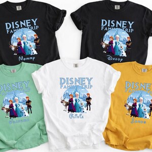 May include: A collection of short-sleeved t-shirts in black, white, green, and yellow. Each shirt features a Disney Family Trip graphic with characters from Frozen and personalized names like "Mommy," "Daddy," "Olivia," and "James."