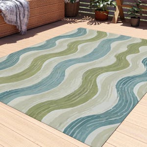 May include: A green, blue, and beige outdoor rug with a wavy pattern. The rug is laid out on a wooden deck.