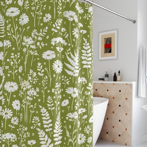 May include: A green shower curtain with a white floral pattern featuring daisies and ferns. The curtain is hanging in a bathroom with a white bathtub and a curved shower rod. The design is a botanical theme.