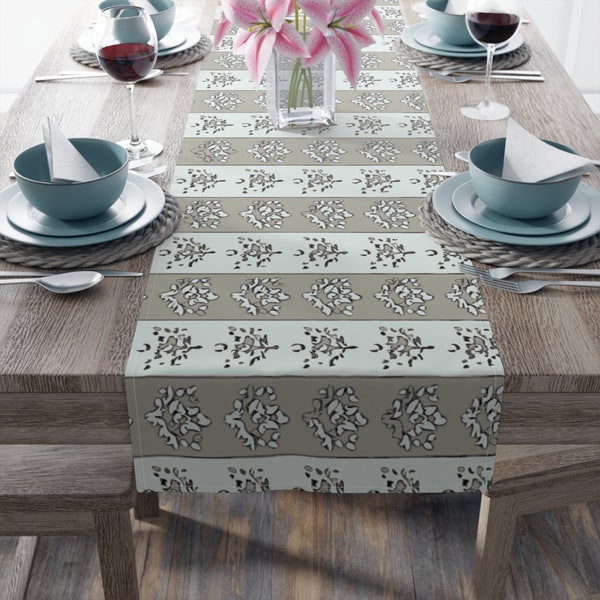 Beige Lotus Table Runner. Beige and white form a tranquil backdrop for stylized lotus flowers, a symbol of strength and resiliency. 2 sizes.