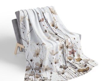 May include: A white throw blanket with a floral pattern featuring brown and pink watercolor flowers on a white background.