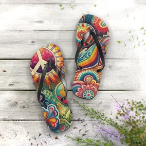 May include: A pair of colorful flip-flops with a peace sign and floral patterns. The flip-flops are on a white wooden surface.