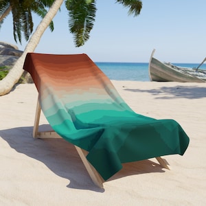 May include: A beach towel with a gradient pattern of orange, brown, green, and blue. The towel is draped over a wooden beach chair on a sandy beach.
