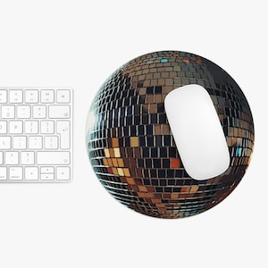 May include: A white computer mouse sits on a round, black and gold disco ball mousepad. The mousepad is made of small, mirrored tiles.