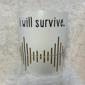 May include: White ceramic planter with gold vertical lines and the text "i will survive."