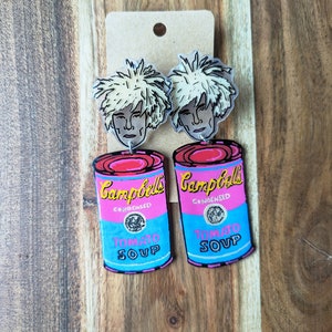 May include: A pair of earrings featuring a pink and blue Campbell's Soup can with the text "Campbell's Condensed Tomato Soup" and a portrait of Andy Warhol.