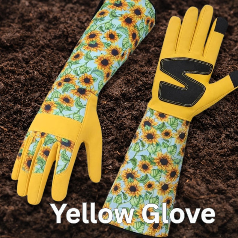 Peut inclure: Une paire de gants de jardinage jaunes avec un motif de tournesols sur les poignets. Les gants ont un motif noir au dos de la main et le texte "Yellow Glove" en blanc.