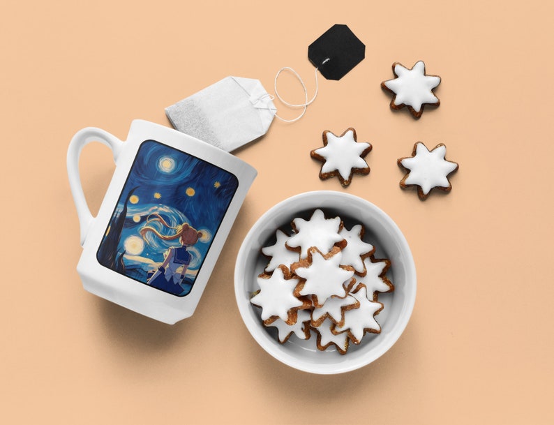 May include: A white ceramic mug with a blue and yellow anime-style illustration of a girl with blonde hair standing in front of a starry night sky. The mug is on a light orange surface with a bowl of white-frosted star-shaped cookies and a tea bag.