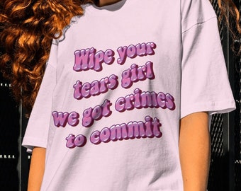 May include: White t-shirt with a pink graphic that says "Wipe your tears girl we got crimes to commit."