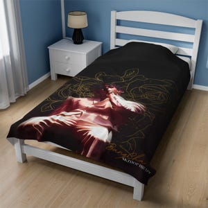 Peut inclure: Drap de lit double noir avec un motif floral doré et une image stylisée d'une personne vêtue d'une tenue blanche et rose. Le texte "Babyface SKZHIPHOP" est imprimé sur le drap.