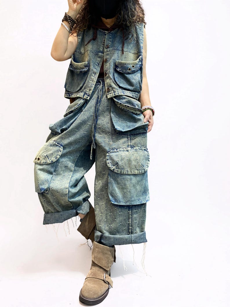 May include: A denim vest and matching cargo pants set in a light blue wash. The vest has multiple pockets and a drawstring. The pants feature oversized pockets and a relaxed fit. The outfit is paired with brown boots.