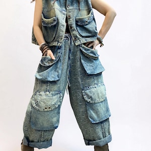 May include: A denim vest and matching pants set in a light blue wash. The vest has a button-up front and multiple pockets. The pants are loose-fitting with large cargo pockets and a drawstring waist. The outfit is paired with brown boots.