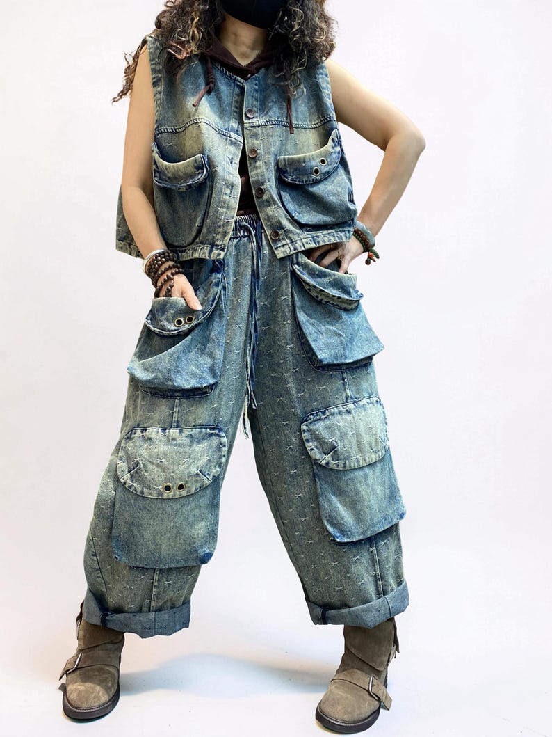 May include: A denim vest and matching pants set in a light blue wash. The vest has a button-up front and multiple pockets. The pants are loose-fitting with large cargo pockets and a drawstring waist. The outfit is paired with brown boots.