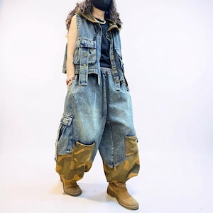 May include: A sleeveless hooded denim vest with front pockets and metal buttons, paired with loose-fitting acid-wash denim cargo trousers featuring large side pockets and brown camouflage fabric panels at the lower legs, worn with tan suede boots.
