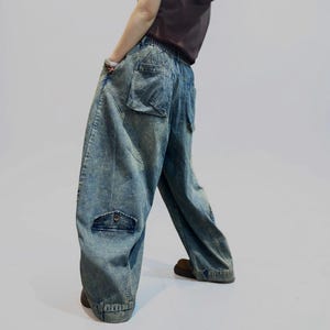 May include: Light blue denim cargo pants with large pockets and a relaxed fit. The pants have a faded wash and a high waist. The model is wearing a brown top and brown shoes. The pants are a stylish and comfortable option for casual wear.