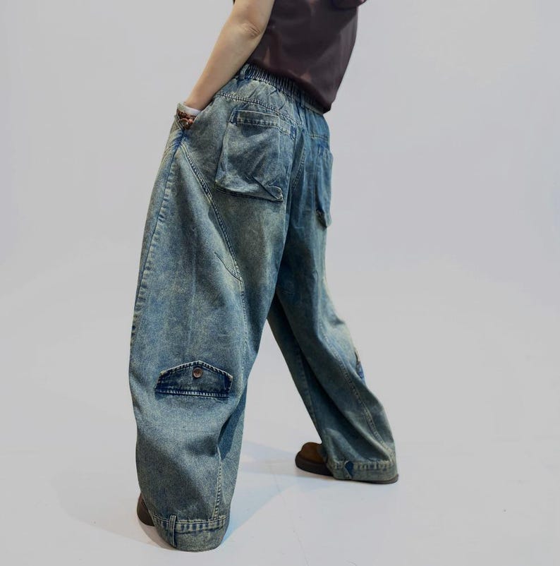 May include: Light blue denim cargo pants with large pockets and a relaxed fit. The pants have a faded wash and a high waist. The model is wearing a brown top and brown shoes. The pants are a stylish and comfortable option for casual wear.