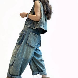 May include: A denim vest and matching cargo pants in a light blue wash. The pants have large pockets and are cuffed at the ankles. A straw hat with a patterned band and brown suede boots complete the outfit. The outfit is casual and stylish.