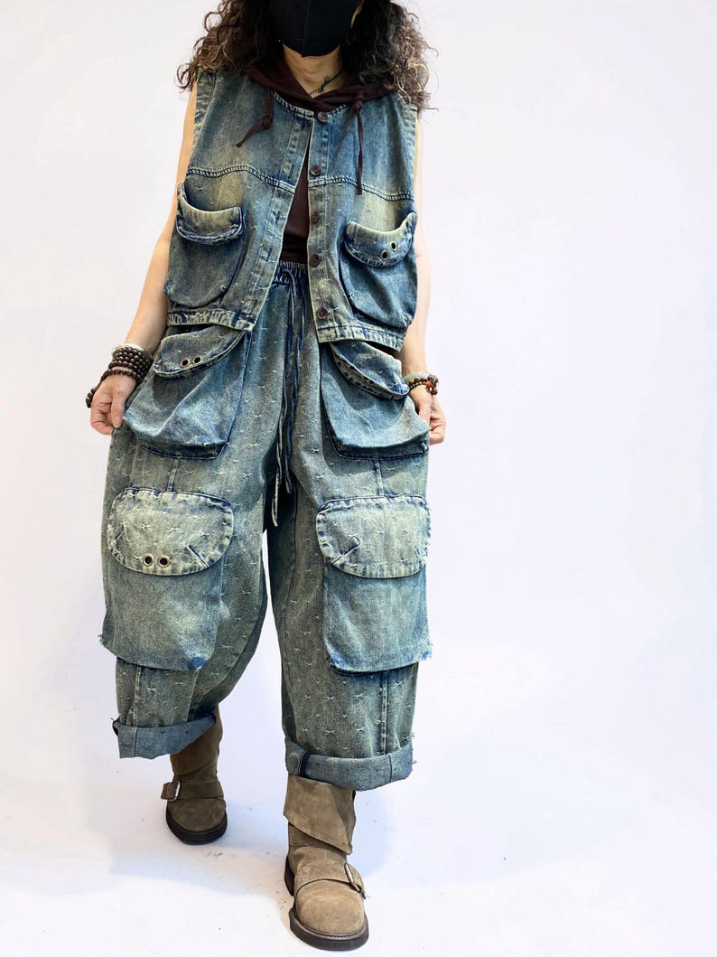 May include: A denim vest and matching pants set in a light blue wash. The vest has multiple pockets and a hood. The pants are loose-fitting with large pockets and rolled-up cuffs. The outfit is worn with brown boots.