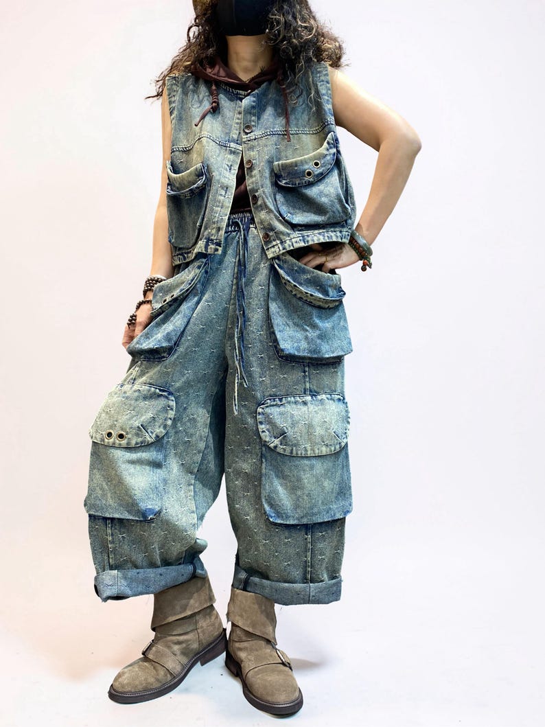 May include: A denim vest and matching cargo pants set in a light blue wash. The vest has multiple pockets and button closures. The pants feature large pockets and a drawstring waist. The outfit is paired with brown boots.