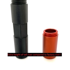 Pode incluir: Dois elevadores impressos em 3D de tamanhos diferentes, um preto e outro laranja. O texto "Extra height of tall riser compared to factory riser!" é visível abaixo dos elevadores.