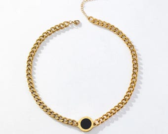 May include: A gold chain necklace with a black circle pendant. The chain is a curb chain style.