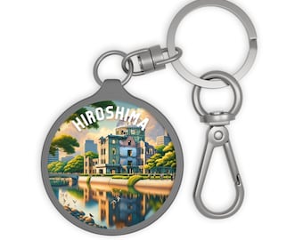 Puede incluir: Un llavero redondo con una colorida ilustración del Memorial de la Paz de Hiroshima. El llavero tiene un anillo y un cierre de metal plateado. La palabra "Hiroshima" está impresa en blanco en la parte superior de la imagen.