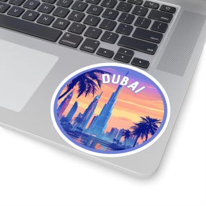 Könnte beinhalten: Ein runder Aufkleber mit einem violetten Rand und einem weißen Hintergrund. Der Aufkleber zeigt eine farbenfrohe Illustration der Skyline von Dubai mit Palmen und dem Text "DUBAI" in weißen Buchstaben.