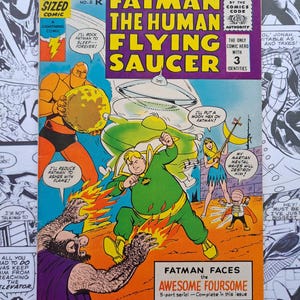 May include: A vintage comic book cover titled "Fatman the Human Flying Saucer" from June 1967. The cover features colourful illustrations of a superhero in a green suit, battling various villains. The comic is a "Giant Sized" issue.