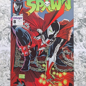 May include: Comic book cover for Spawn #8, featuring a dynamic illustration of the character in a red cape and spiked gauntlets. The title "Spawn" is in green and yellow, with the Image Comics logo and issue details visible.